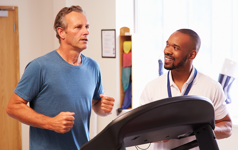 man using treadmill in rehab with doctor