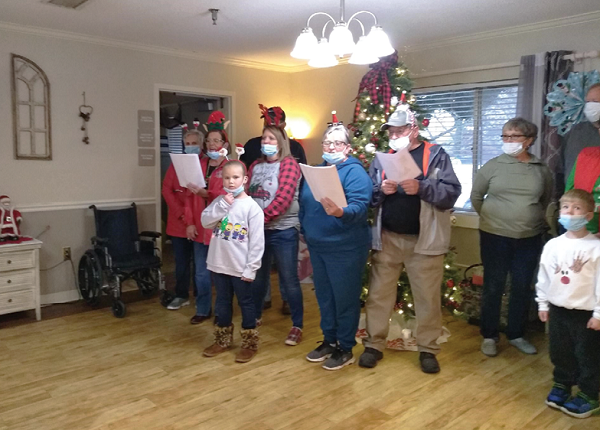 group of adults and children singing Christmas Carols