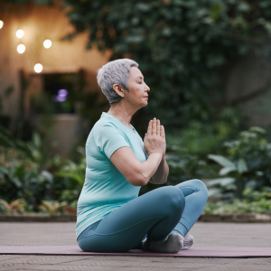 middle aged woman meditating in zen garden