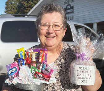 Photo of older adult woman smiling for photo holding gift basket prizes